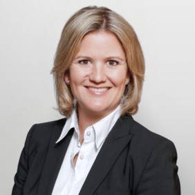 Eva Meinecke - Vice President Governance & Corporate Functions Portrait einer Frau mit blonden, schulterlangen Haaren, die in einem schwarzen Blazer und weißem Hemd gekleidet ist. Sie lächelt freundlich und schaut direkt in die Kamera. Der Hintergrund ist hell und schlicht.